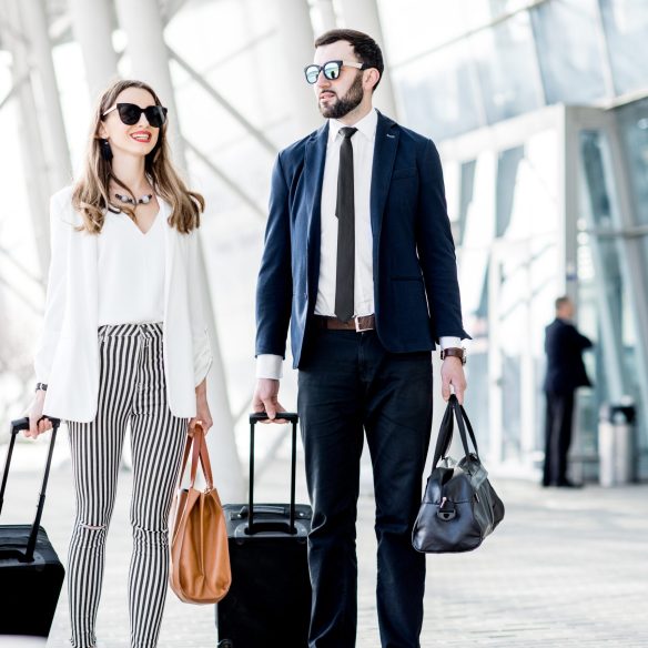 Business couple walking with luggage near the airport during the business trip